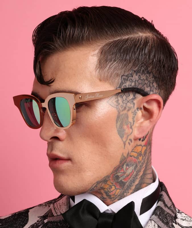 Side view of a man with a slicked drop fade haircut, side part, and visible neck tattoo, wearing sunglasses.