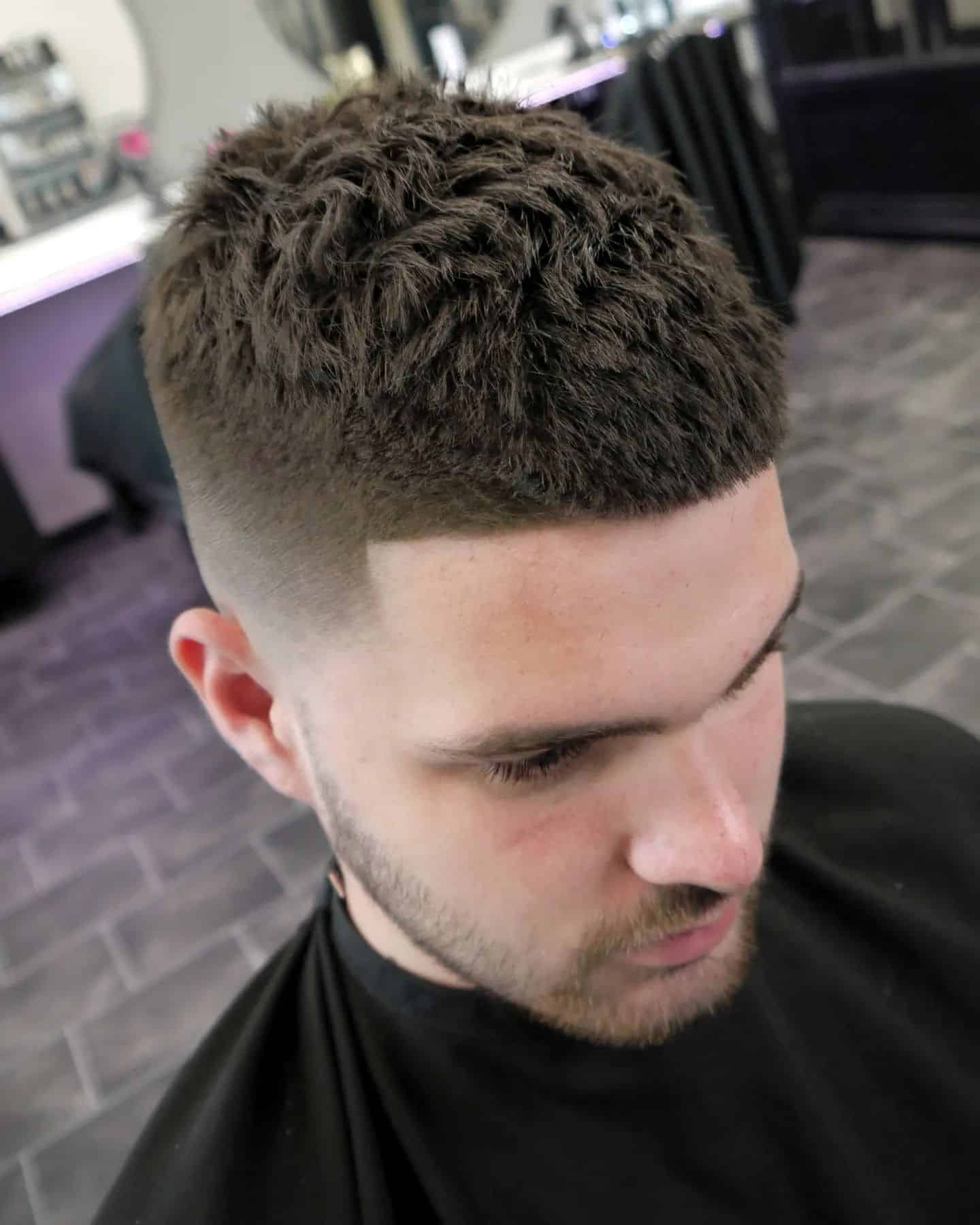 Close-up of a textured, low-maintenance men's haircut with a high fade and natural, tousled top