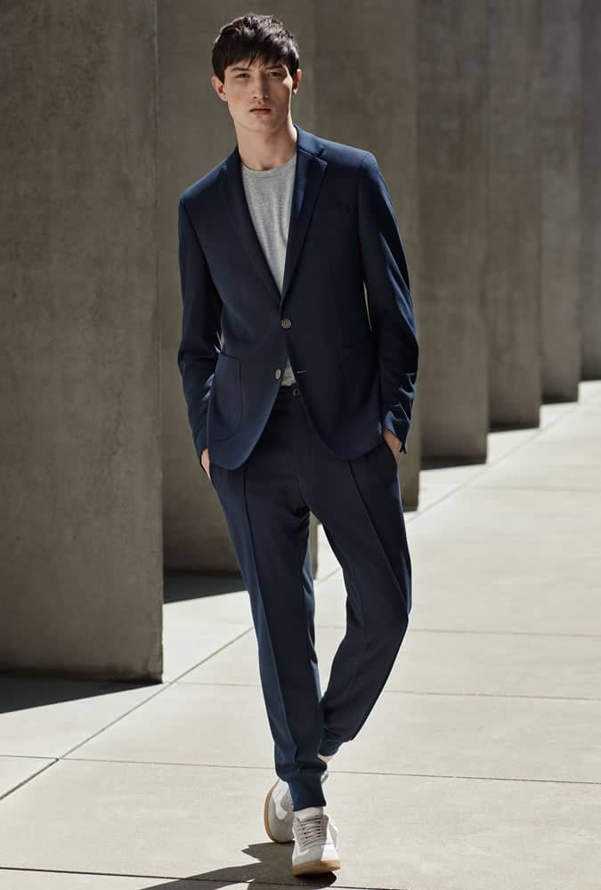 Man in a casual navy suit paired with a gray T-shirt and white sneakers, showcasing a modern smart-casual style.