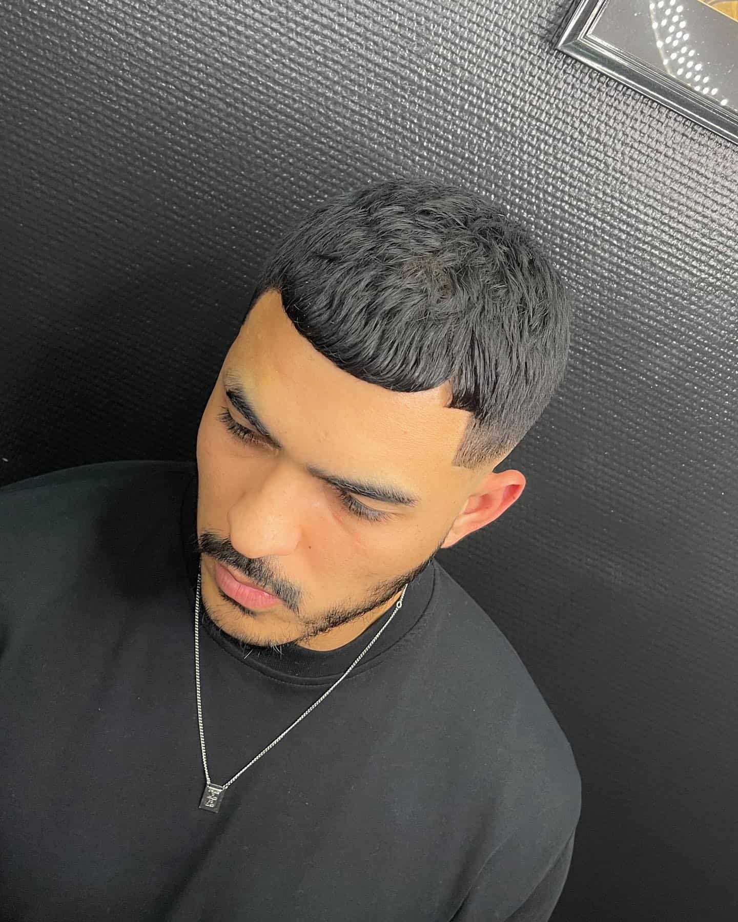 Close-up of a men’s cropped fringe haircut with a low fade and textured top.