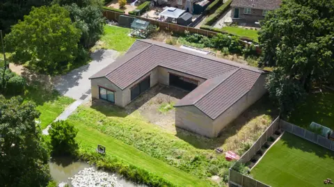 Getty Images The 'Captain Tom Foundation building' that was built beside the Ingram-Moores' home. It is a birds eye view photo. A green lawn and river are visible.