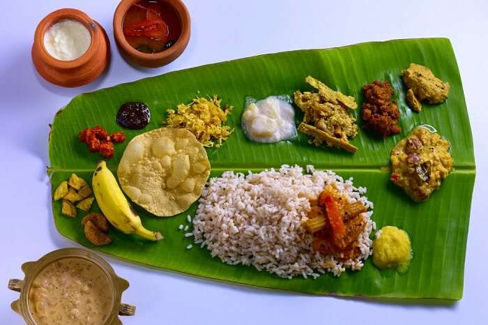 Ela Sadya, a traditional Kerala feast served on a banana leaf, featuring rice, curries, pickles, papadam, and desserts