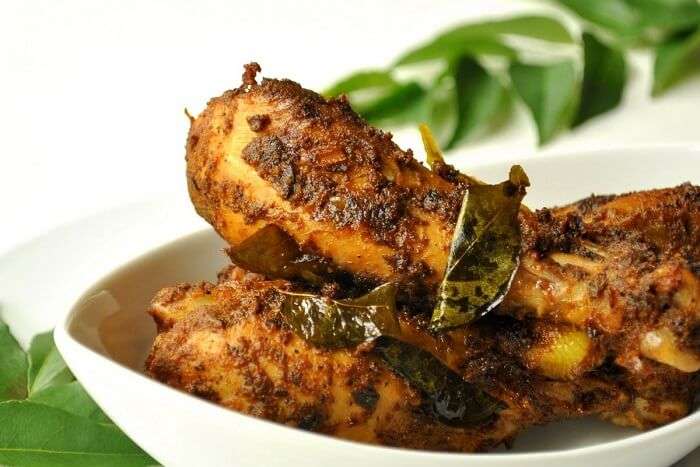 Nadan Kozhi Varuthathu, a Kerala-style spicy fried chicken garnished with curry leaves, served in a white bowl.