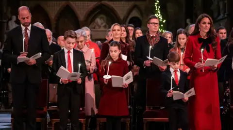 PA Media (left to right) Prince William, Prince George, Princess Charlotte, Prince Louis, and Princess Catherine standing in Westminster Abbey during the carol service. They are at the front and rows of people behind them.