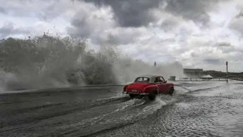 Getty Images A car driving through storm water in Havana, the Cuban capital