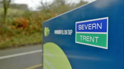 A Severn Trent sign showing its blue and green logo by the side of the road