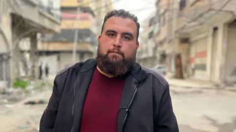 Aamir Peerzada/BBC Abdul Rahman Hijazi standing in the middle of a street, looking straight into the camera