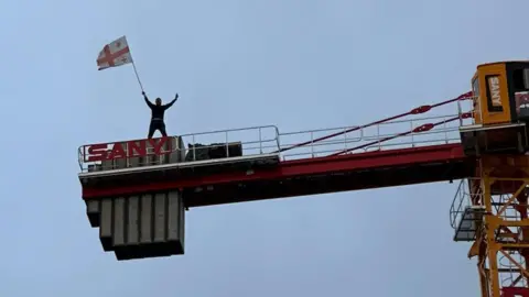 Nino Kereselidze A Georgian flag is waved from a crane at protesters passing underneath