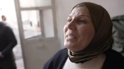 A woman in a brown headscarf crying. 