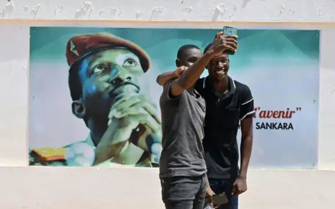 AFP Students dressed in black take a selfie next to an image of Thomas Sankara, a pan-Africanist icon, at the University Thomas Sankara near Ouagadougou in Burkina Faso on 15 October 2021