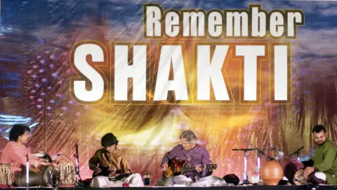 AFP  Tabla maestro Ustad Zakir Hussain (L), mandolin player U.Srinivas (2nd L), guitarist John McLaughlin (2nd R) and kanjira player V.Selvaganesh perform at a concert in Bangalore 30 January 2003. The group formed in the 80's called "Shakti" performed a few of thier old numbers and presented a fusion ensemble of western jazz and traditional Indian styles. 