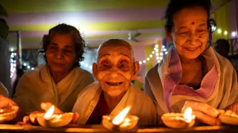 Getty Images Elderly women at Pramod Talukdar Memorial Old Age Home light Diya oil lamps as they celebrate Diwali in Guwahati, India, on November 1, 2024