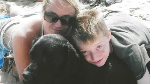 Family photo Declan as a child, lying on the beach with his mum Alex and his dog