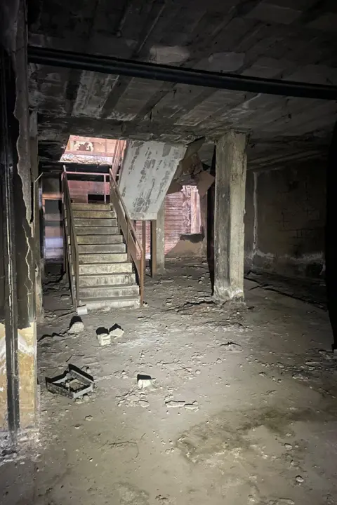 View of stairs leading down into an underground hospital with rubble on floor and ceiling caved in