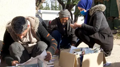 BBC/Thanyarat Doksone Relatives of missing people in Syria search records, passports and other documents