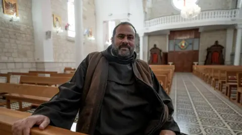 Lee Durant/BBC Bearded man sits on a pew in a church