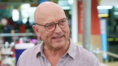 BBC/SHINE TV A picture of Gregg Wallace wearing a light coloured shirt against a colourful background