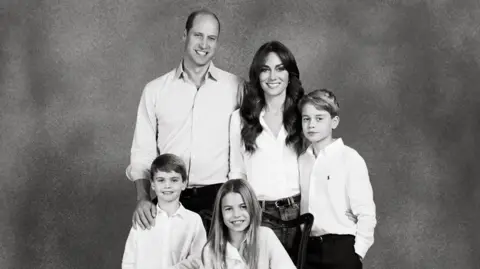 PA Media Prince William and Catherine with their children in their 2023 card. The couple and their three children are dressed in smart, casual clothes, in a black-and-white photograph.