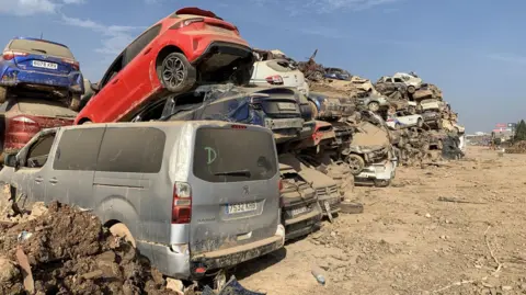 Guy Hedgecoe Vehicles that were damaged in the floods piled on top of each other