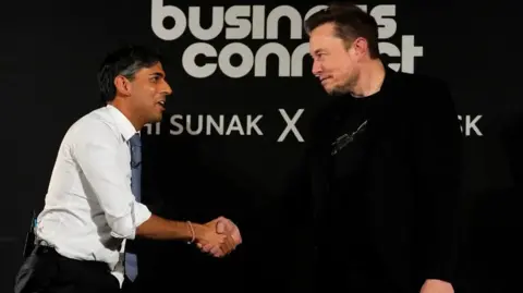 Reuters A man in a white shirt and tie shakes hands with a man in a dark top on a conference stage