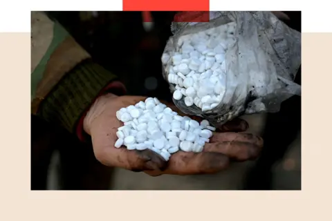 Getty Images A treated image shows a dirty hand holding a pile of white pills, being poured from a bag