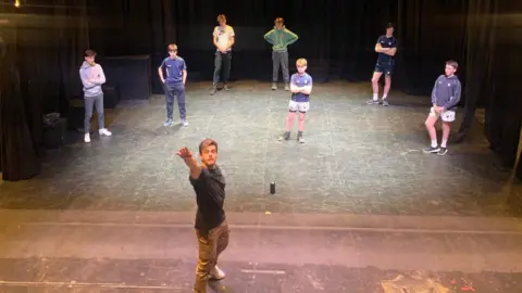 Bedford School Jonno is on a stage at Bedford School gesturing. He is teaching a group of children stood behind him acting techniques.