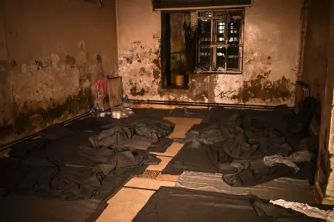 Getty Images A picture shows a prison cell with blankets and makeshift beds on the floor, in the basement of the Syrian General Security Directorate Branch 251, also known as Al-Khatib branch