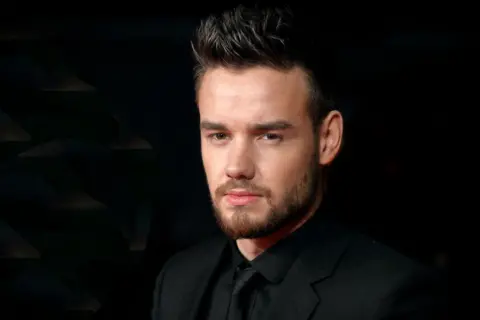 Getty Images Publicity shot of Liam Payne wearing black against a black background. He has gelled hair and a neat beard and is looking moodily into the camera.