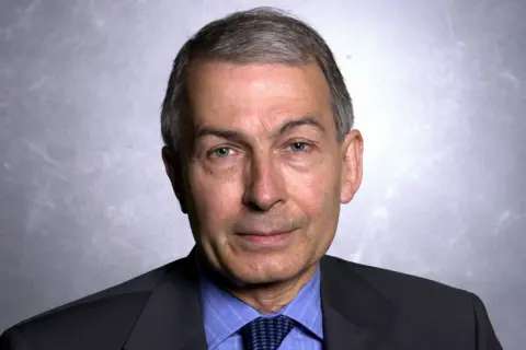 Jeff Overs/BBC Head and shoulders shot of Frank Field. He has very neatly cut and combed grey hair, and looks into the camera. He is photographed against an anonymous background and is wearing a dark suit with blue shirt and tie.