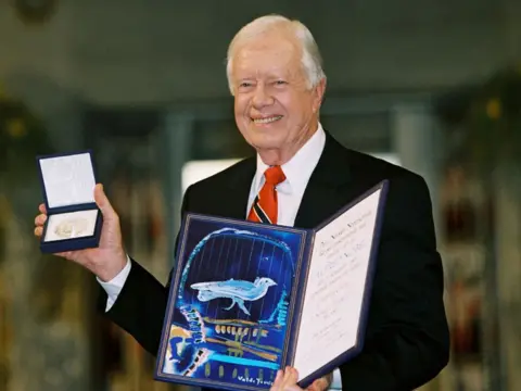 Getty Images ormer US President Jimmy Carter holds up his Nobel Peace Prize December 10, 2002 in Oslo, Norway. 