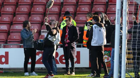 Getty Images Wrexham co-owner Rob McElhenney pitch-side and surrounded by a film crew for the documentary Welcome to Wrexham 