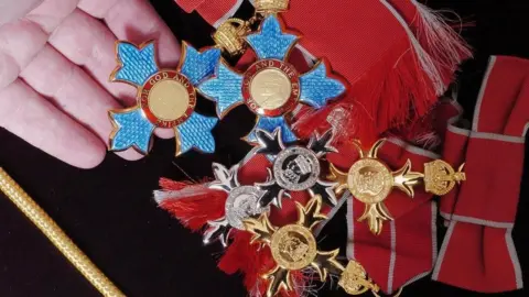 PA Media A number of different medals on a red and black uniform 