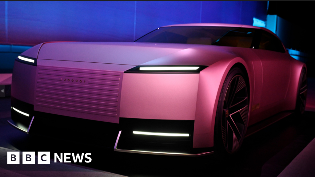 A sleek and futuristic pink Jaguar electric concept car, showcasing bold design and innovative lighting features, under dramatic showroom lighting.