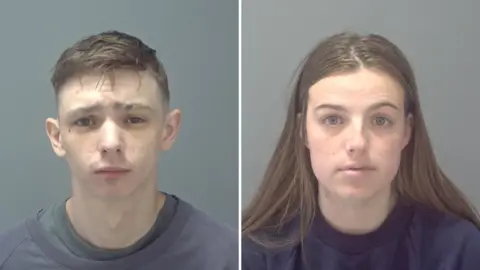 Suffolk Police Mugshots of Scott Jeff and Chelsea Gleason-Mitchell. Jeff is on the left, wearing a grey sweatshirt and looking directly at the camera. Gleason-Mitchell is on the right, wearing a navy sweatshirt and she has long brown hair. 