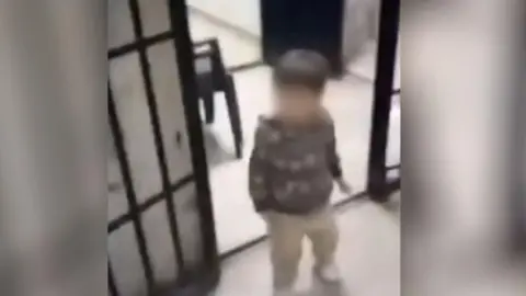 ADMSP A toddler, no more than 3 or 4 years of age, walks through an open cell door.