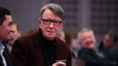 Getty Images Lord Mandelson clutching a coffee cup and wearing dark rimmed glasses at a Labour Party event