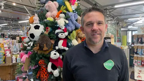 Charlie Groves, managing director of Groves Garden Centre in Bridport, Dorset standing in front of a Christmas tree covered in Jellycat soft toys