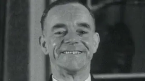 Reuters A screenshot from a black and white archive film from 1952.  Albert Gunter is smiling proudly and wearing his bus driver uniform.