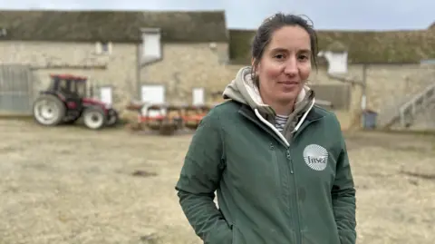 Lisa Louis French farmer Alix Heurtault stands on her farm with a tractor in the background