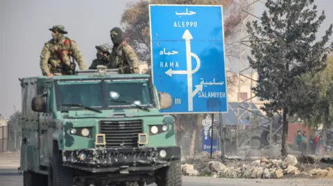 Getty Images Anti-Assad fighters sit in an armoured van while advancing through Homs, the gateway to the capital Damascus