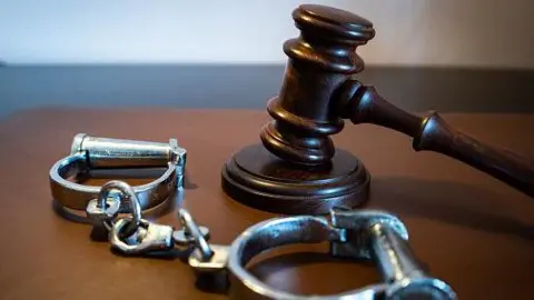 Getty Images stock photo of a gavel and handcuffs on a leather surface
