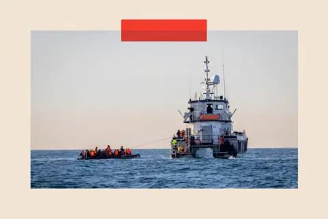 Getty Images A small boat packed with people is rescued in English waters by a larger boat