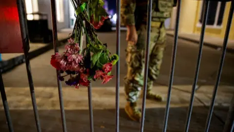 Reuters A military personnel stands near flowers on a fence near the scene