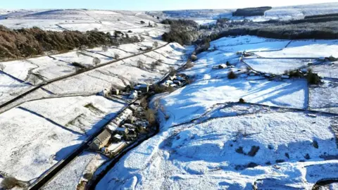 PA Media An aerial photo showing fields and homes covered in snow in Allenheads, Northumberland