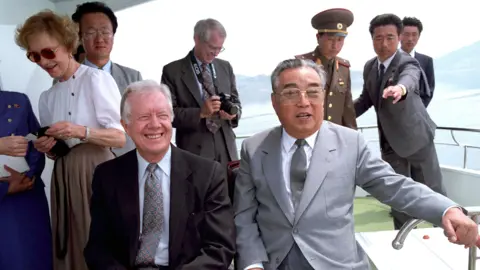 AP Former President Jimmy Carter and,. behind him, former First Lady Rosalynn Carter with Kim Il Sung aboard the North Korean leader's yacht during their 1994 visit to Pyongyang. (SINGLE USE ONLY. DO NOT REUSE)