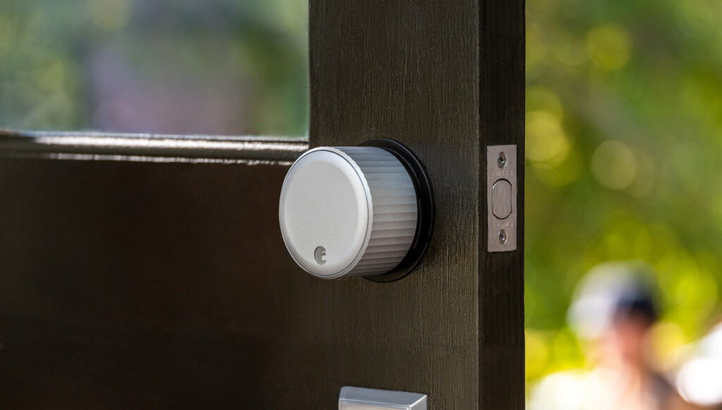 An August Wi-Fi Smart Lock installed on a door, offering keyless entry and remote access via a smartphone app.